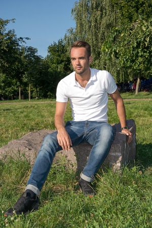 Man resting on a stone in a summer parkの写真素材