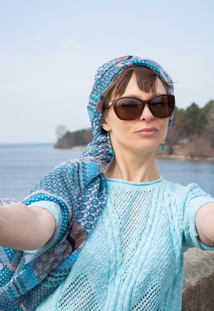 Beautiful woman taken picture of herself, selfie. Young woman photographed herself in front of the seascape.の写真素材