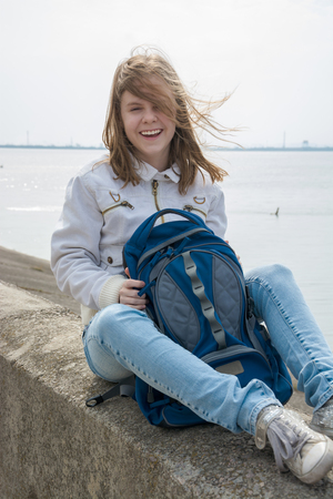 A teenage girl with a backpack and sneakers in front of the seaの写真素材