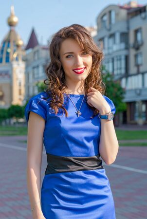 A young woman in front of the cityscape. Model in blue dress in front of buildings in a European city.の写真素材