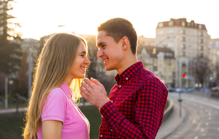 A young woman talking to a man and laughing at the cityscape background at sunset