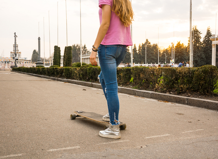 Legs of a hipster teenager-girl is riding a skateboard in a abandoned park in summer, closeup.の写真素材