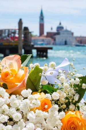 A bouquet of a orange roses at the San Giorgio Maggiore island background in tne lagoon of Venice background, Italyの写真素材