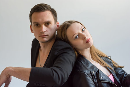 Young couple in love posing in the studio. Man and woman in leather jackets.