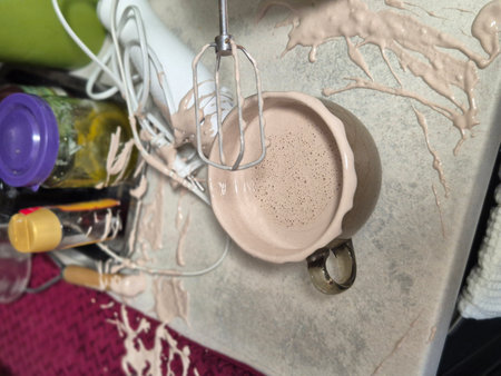 The process of making the cream, accidentally splattered mixture, splattered on the kitchen table - mixer, jar of honey, bottle of sauce, cup, mat for drying dishesの写真素材