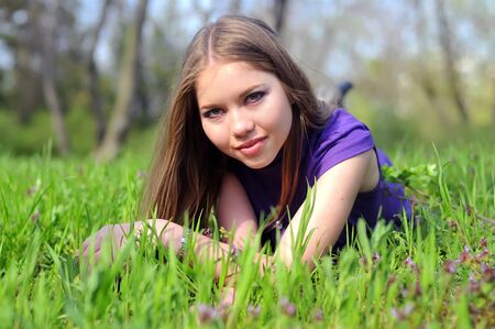 young girl is laying on green grassのeditorial素材