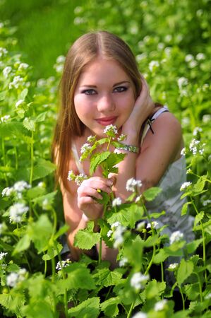 young girl is sitting on a green grassの写真素材