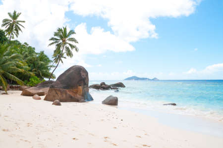 Beautiful beach in Seychelles with rocks and palm trees, blue Indian Ocean and picturesque sky.の写真素材