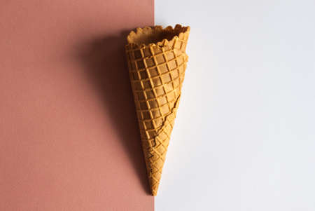 Ice cream waffle cone on terra-cotta and light gray, pastel minimal flat lay top view. の写真素材