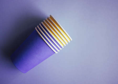 Yellow and purple paper cups on blue background. Set for party.の写真素材