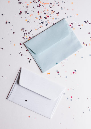 White and gray envelops on light festive background with sparkles. Flat lay style.