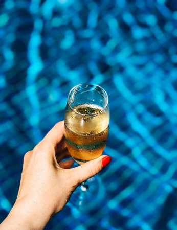 Glass of Champagne in hand in pool. Festive concept.
