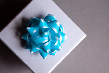 Gift box with blue bow on dark gray background. Flat lay. Festive concept.