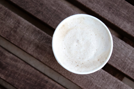 Cap of cappuccino in paper on bench. Outdoor concept.