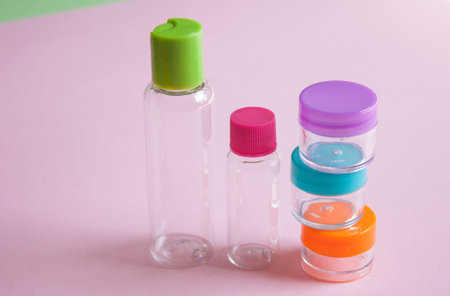 Travel size cosmetic and creams bottles set on pink background. Minimalism cosmetics style. Top...