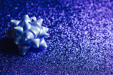 Ultraviolet abstract bokeh background and lilac bow, defocused Christmas lights. Festive concept....
