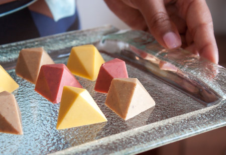 Colorful chocolate vegan pralines on glass tray.