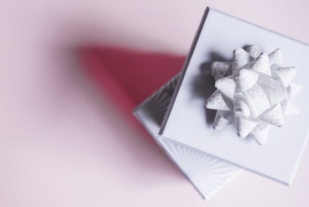 Two light gray gift boxes with light bow on lilac background. Festive concept.