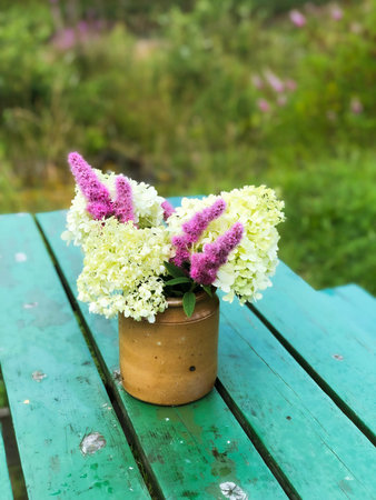 Beautiful seasonal flowers in vase on green wooden table in Norway.
