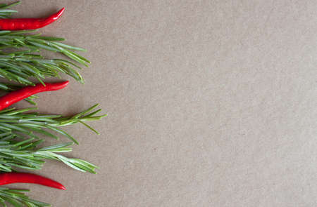 Fresh sticks of rosemary and red cayenne pepper on kraft paper background.の写真素材