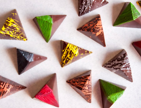 Dark chocolate colorful pralines on white background.