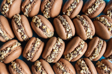 Dark chocolate macarons with cashew nuts background.
