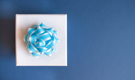 Gift box with light blue bow on dark background. Flat lay. Festive trendy minimal concept.の写真素材