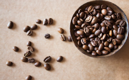 Coffee beans on dark wooden handmade spoon on brown kraft paper.