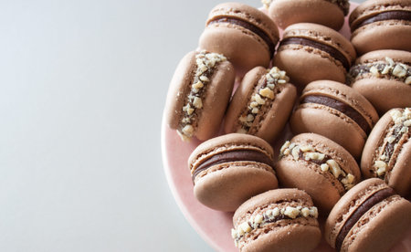 Pink plate with dark chocolate macarons on silver background. Festive concept.