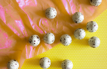 Delicious chocolate Easter eggs candies on pinkish yellow background. Holiday concept.
