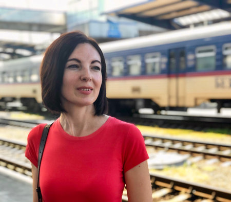 Young beautiful brunet woman waiting for train on railway station in Europe.