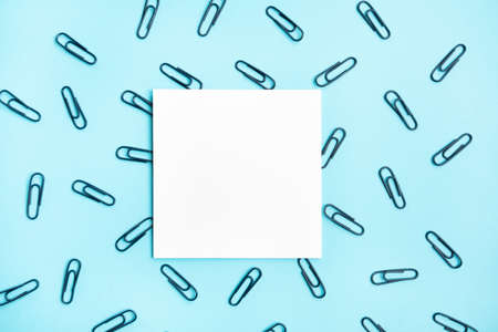 White square frame with dark paper clips on trendy blue background. Flat lay minimalistic style. Trendy color.の写真素材