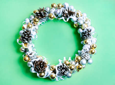 White, silver and golden ornaments Christmas wreath on trendy mint green background. Modern festive concept.の写真素材