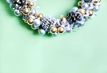 White, silver and golden ornaments Christmas wreath on trendy green background. Modern festive concept.の写真素材