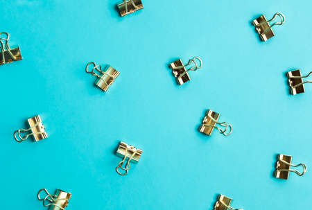 Golden paper clips pattern on trendy blue background. Top view, flat lay. Minimal school or office stationery.の写真素材