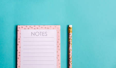 Pink notebook and cute golden pencils on trendy green background. Flat lay minimalism style.の写真素材