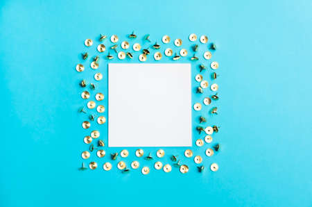 White square frame with golden shiny pushpins on trendy blue background. Flat lay minimalistic style. Trendy color.の写真素材