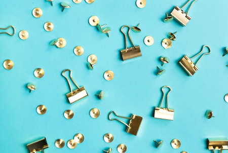 Golden paper clips and pushpins pattern on trendy blue background. Top view, flat lay. Minimal school or office stationery.の写真素材