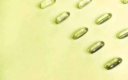 Bright green gel pills on yellow background. Healthcare concept.の写真素材