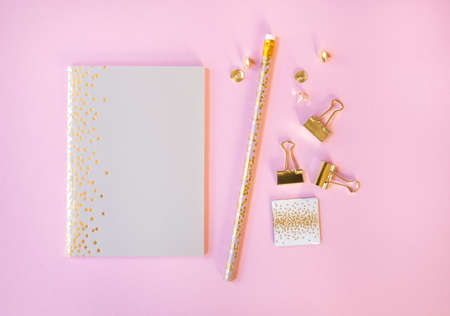 Beige notebook and pencil with golden polka dot print on light pink background. Flat lay style.の写真素材