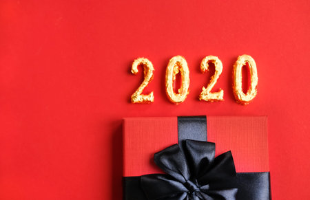 Golden 2020 and gift box on trendy Christmas red background. Flat lay style.の写真素材