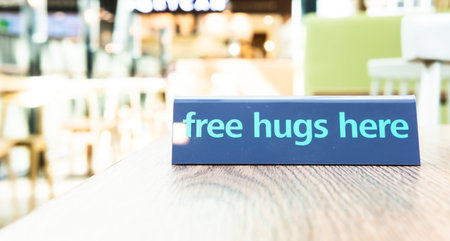 Free hugs sign in trendy mint green color on wooden table in cafe. Modern social concept. 