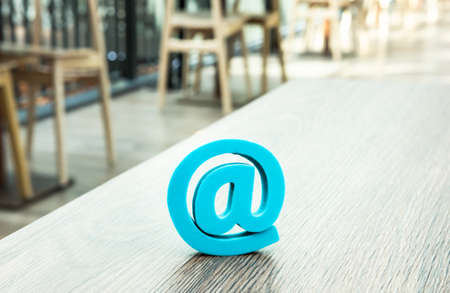 Trendy mint blue at sign at desktop in cafe. Email symbol concept. の写真素材