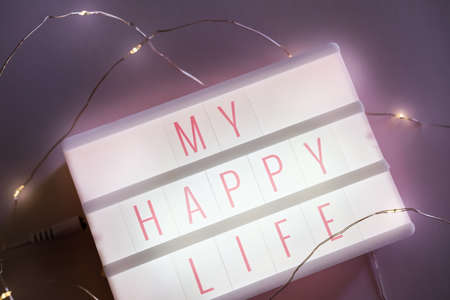 Pastel pink magnet micro led light box with sentence my happy life on dark background.の写真素材
