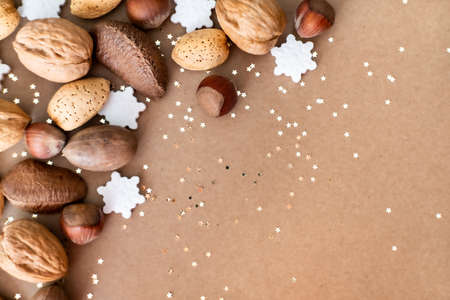 Golden Christmas star glitter, white sugar snowflakes and different nuts on natural kraft background. Flat lay style. Holiday classic concept.の写真素材