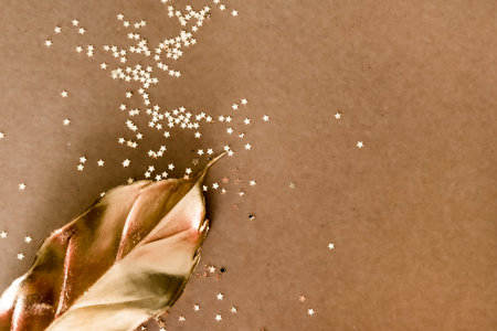 Golden decorations and star shaped glitters on natural kraft background. Flat lay style. Holiday...