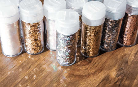 Plastic containers with metallic shiny glitter, holidays decor set on wooden background. Magic festive concept.の写真素材