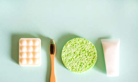 Cosmetic products, soap, bamboo toothbrush and facial sponges on green background. Beauty concept. Flat lay design.の写真素材