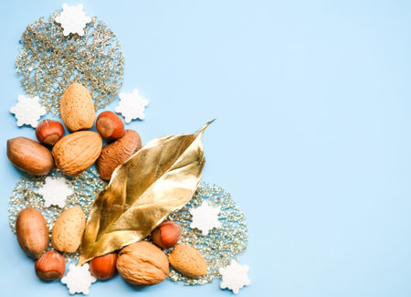 Golden decor, nuts, snowflake sprinkles and shiny star shaped glitters on pastel blue background....