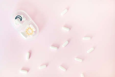 Pill case and white tablets on pink background. Top view, healthcare concept.の写真素材